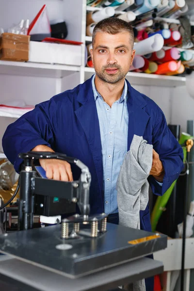 Manliga arbetaren gör tryck på skjorta — Stockfoto