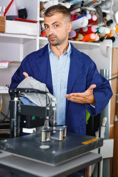 Male worker makes print on shirt — Stock Photo, Image