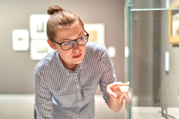 woman visitor in historical museum looking at art object