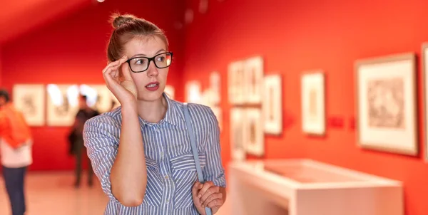 Flicka besökare stående nära bilder i konstmuseet — Stockfoto