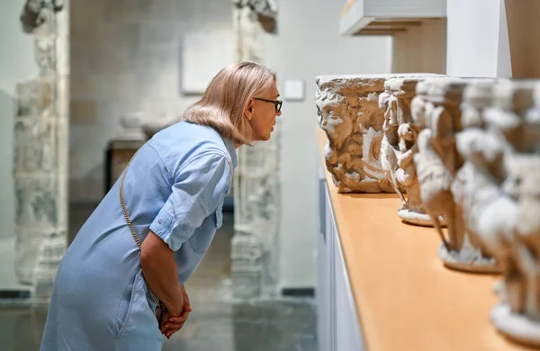 Woman in historical museum looking at art object.