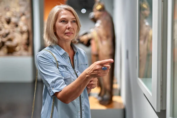 Mulher madura visitante no museu histórico olhando para fotos — Fotografia de Stock