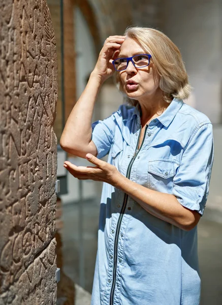 Mujer madura hermosa chica considera exposiciones en el museo . — Foto de Stock