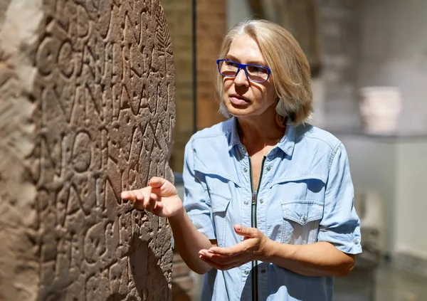 Mulher estudando hieróglifos de escrita antiga no museu de artes — Fotografia de Stock