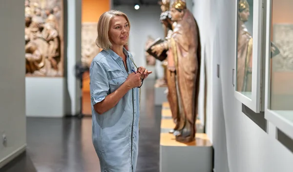 Mulher madura visitante no museu histórico olhando para fotos — Fotografia de Stock