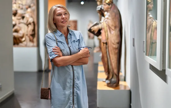 Mulher madura visitante no museu histórico olhando para fotos — Fotografia de Stock