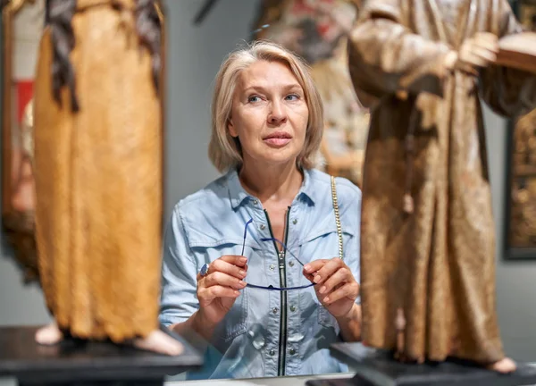 Mulher madura visitante olhando objeto de arte na galeria de arte museu . — Fotografia de Stock