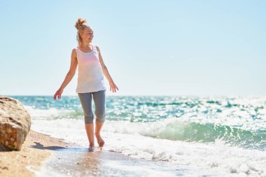 Happy senior woman walks by the sea.