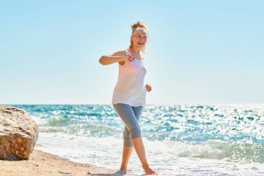 Happy senior woman walks by the sea.