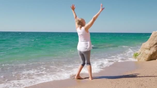 Gelukkig senior vrouw loopt door de zee. — Stockvideo