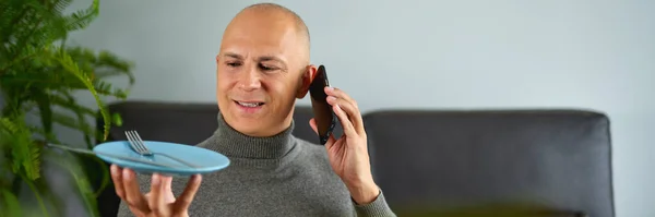Muž mluví na mobilním telefonu na pohovce — Stock fotografie