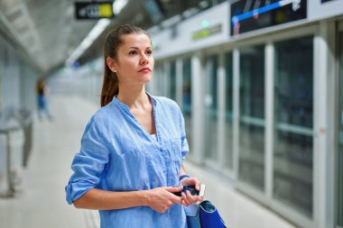 Metro istasyonunda el çantalı genç bir kadın..