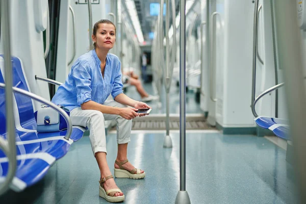 Brunette meisje met behulp van mobiele telefoon in de metro. — Stockfoto