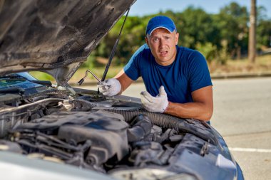 Şehir yolunda eski bir araba kazasının önünde üzgün bir sürücü var.