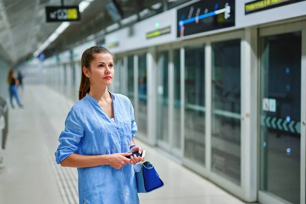 지하철 역에서 가방을 든 젊은 여자가 열차가 도착하기를 기다리고 있다 — 스톡 사진