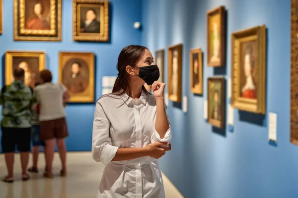 Vrouw bezoeker draagt een antivirusmasker in het historische museum om foto 's te bekijken. — Stockfoto