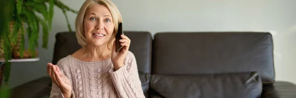 Seniorin Benutzt Handy Während Sie Auf Sofa Sitzt — Stockfoto