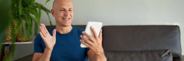Adam kanepede oturuyor ve dijital tablet kullanıyor. Evdeki tablet üzerinden internet taraması.