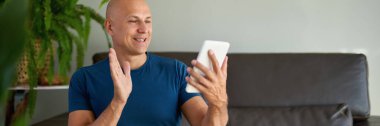 Adam kanepede oturuyor ve dijital tablet kullanıyor. Evdeki tablet üzerinden internet taraması.
