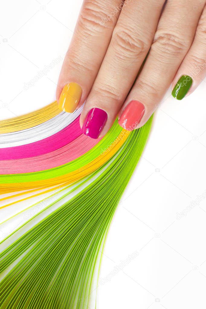 Colorful multi-colored manicure on short nails on white background.Nail art.Pink, green ,yellow, peach nail Polish.