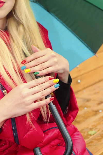 Autumn nail design.Multicolored manicure on a young girl with long hair with an umbrella .Nail art.