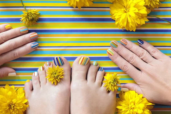 Colorful striped fashion summer pedicures and manicures for women's short nails with yellow flowers.Nail art.