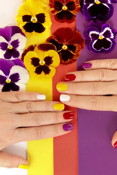 Разноцветный Сочный Маникюр Коротких Женских Ногтях Полосатом Фоне Цветами Pansies — стоковое фото