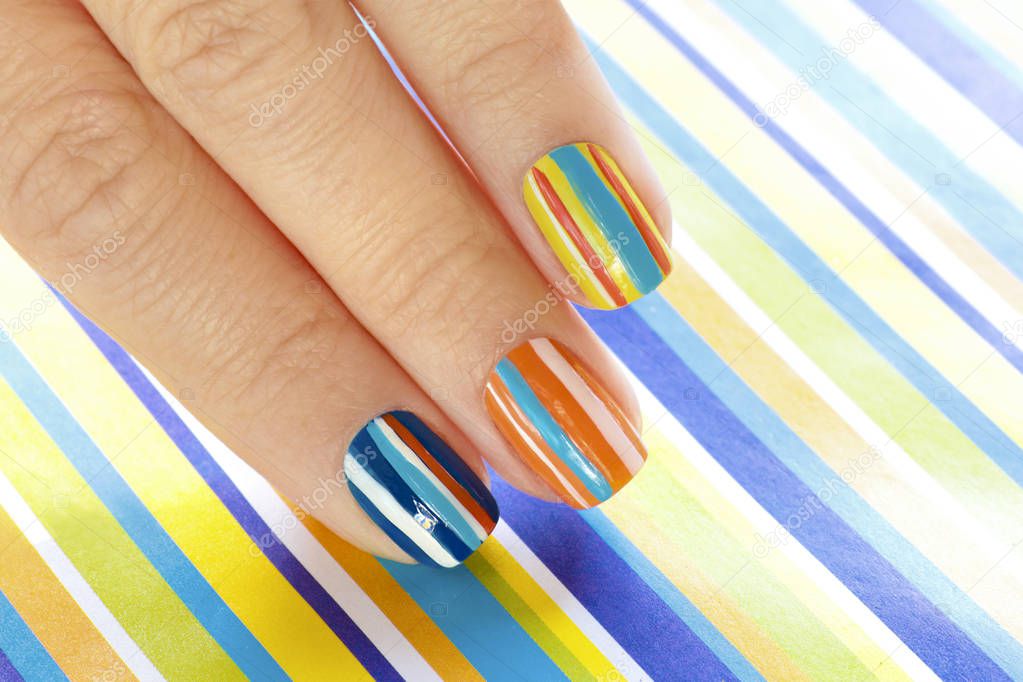 Multi-colored manicure on short nails on striped background. Striped design.Nail art.