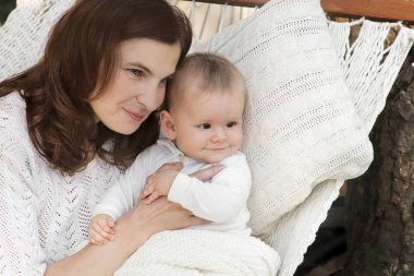 Yaz aylarında bir hamakta küçük oğlu olan anne. Kadın ve çocuk. Aile değerleri.
