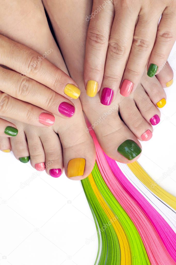 Multicolored bright manicure and pedicure with color lines on a white background close-up.
