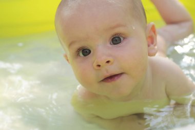Su yordamlar. Yeni doğan bir çocuk yaz aylarında suda yüzüyor. Sağlıklı bebek.