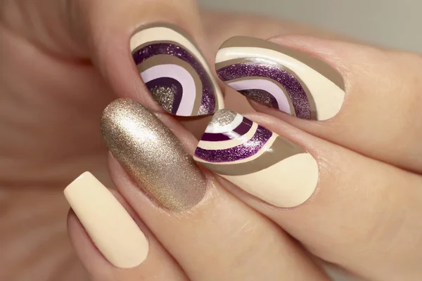 Manicure on a different form of nails with a brilliant varnish on a background of a beige and violet varnish. Nails art.
