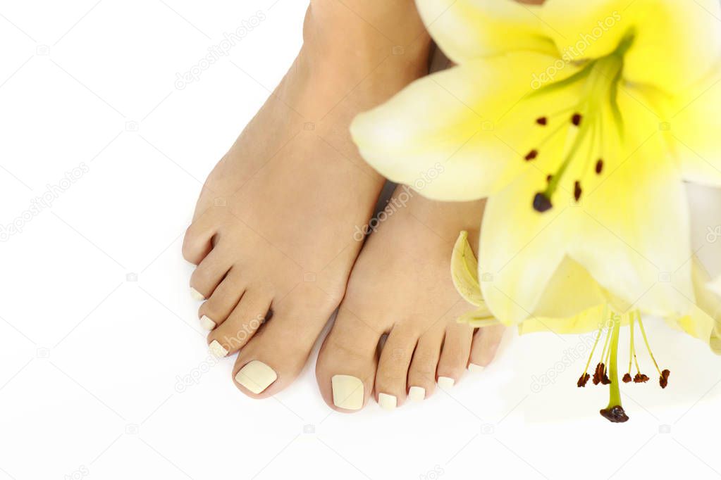 Manicure and pedicure at a long oval shaped nails with yellow lilies on a white background.