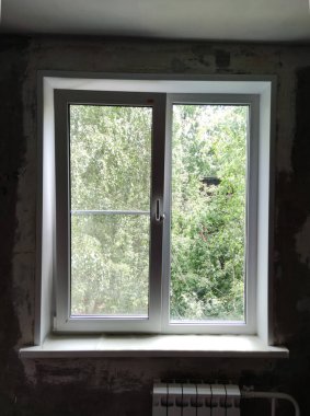 Yazın yeşil ağaç manzaralı plastik beyaz pencere..