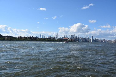 New York City - Haz 30: Manhattan Manzarası, New York, Brooklyn'deki Domino Park'tan, 30 Haziran 2019'da görüldüğü gibi. New York, ABD'nin nüfusa göre en büyük şehridir ve yıllık milyonlarca ziyaretçisi vardır..