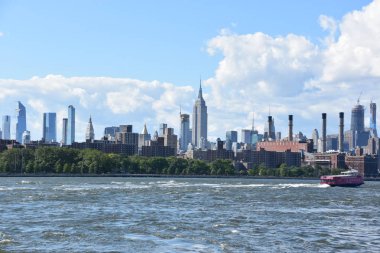 New York City - Haz 30: Manhattan Manzarası, New York, Brooklyn'deki Domino Park'tan, 30 Haziran 2019'da görüldüğü gibi. New York, ABD'nin nüfusa göre en büyük şehridir ve yıllık milyonlarca ziyaretçisi vardır..