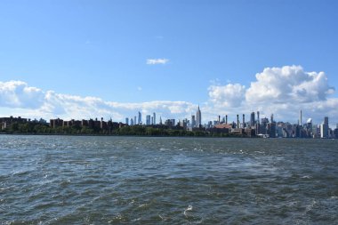 New York City - Haz 30: Manhattan Manzarası, New York, Brooklyn'deki Domino Park'tan, 30 Haziran 2019'da görüldüğü gibi. New York, ABD'nin nüfusa göre en büyük şehridir ve yıllık milyonlarca ziyaretçisi vardır..