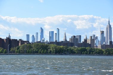 New York City - Haz 30: Manhattan Manzarası, New York, Brooklyn'deki Domino Park'tan, 30 Haziran 2019'da görüldüğü gibi. New York, ABD'nin nüfusa göre en büyük şehridir ve yıllık milyonlarca ziyaretçisi vardır..