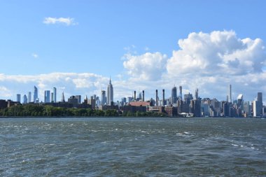 New York City - Haz 30: Manhattan Manzarası, New York, Brooklyn'deki Domino Park'tan, 30 Haziran 2019'da görüldüğü gibi. New York, ABD'nin nüfusa göre en büyük şehridir ve yıllık milyonlarca ziyaretçisi vardır..