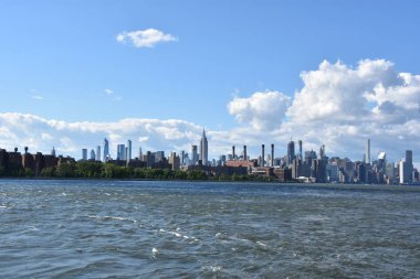 New York City - Haz 30: Manhattan Manzarası, New York, Brooklyn'deki Domino Park'tan, 30 Haziran 2019'da görüldüğü gibi. New York, ABD'nin nüfusa göre en büyük şehridir ve yıllık milyonlarca ziyaretçisi vardır..