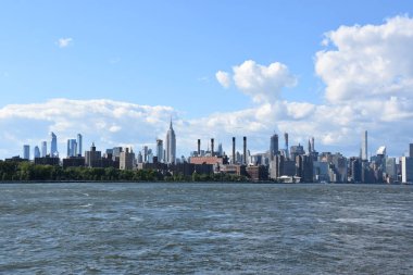 New York City - Haz 30: Manhattan Manzarası, New York, Brooklyn'deki Domino Park'tan, 30 Haziran 2019'da görüldüğü gibi. New York, ABD'nin nüfusa göre en büyük şehridir ve yıllık milyonlarca ziyaretçisi vardır..