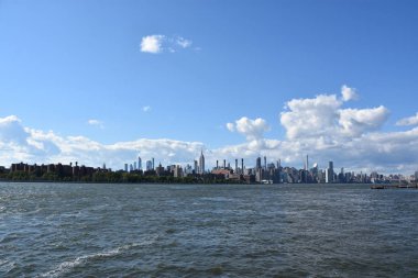 New York City - Haz 30: Manhattan Manzarası, New York, Brooklyn'deki Domino Park'tan, 30 Haziran 2019'da görüldüğü gibi. New York, ABD'nin nüfusa göre en büyük şehridir ve yıllık milyonlarca ziyaretçisi vardır..