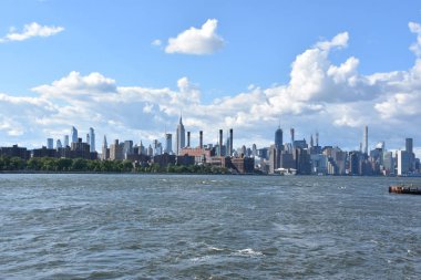 New York City - Haz 30: Manhattan Manzarası, New York, Brooklyn'deki Domino Park'tan, 30 Haziran 2019'da görüldüğü gibi. New York, ABD'nin nüfusa göre en büyük şehridir ve yıllık milyonlarca ziyaretçisi vardır..
