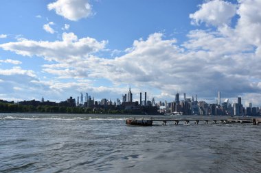 New York City - Haz 30: Manhattan Manzarası, New York, Brooklyn'deki Domino Park'tan, 30 Haziran 2019'da görüldüğü gibi. New York, ABD'nin nüfusa göre en büyük şehridir ve yıllık milyonlarca ziyaretçisi vardır..