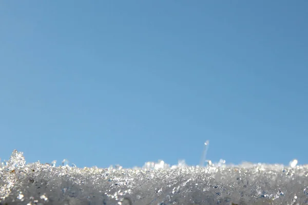 Bir kar tabakası masmavi gökyüzüne karşı parlak güneş altında parlıyor.