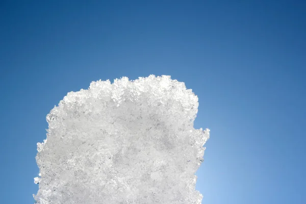 Bir kar tabakası masmavi gökyüzüne karşı parlak güneş altında parlıyor.