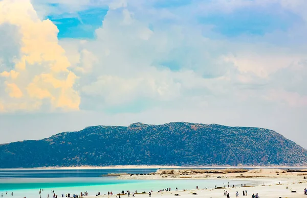 İnsanlar solgun gölün beyaz kıyısında dinleniyor Salda dağların ve mavi gökyüzünün arka planında