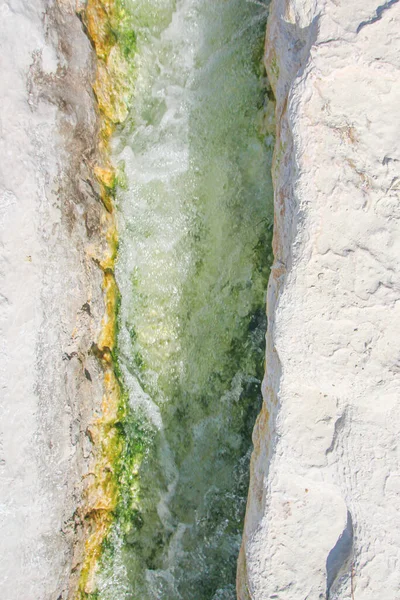 Dağlarda yeşil suyu olan bir derenin arka planı Pamukkale geçitlerindeki bir yarıktan akar.