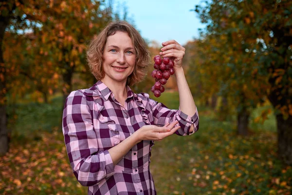 Vrouw met druiven in de tuin — Stockfoto