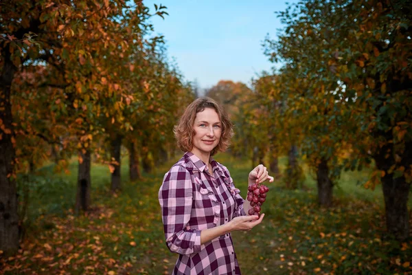 Vrouw met druiven in de tuin — Stockfoto